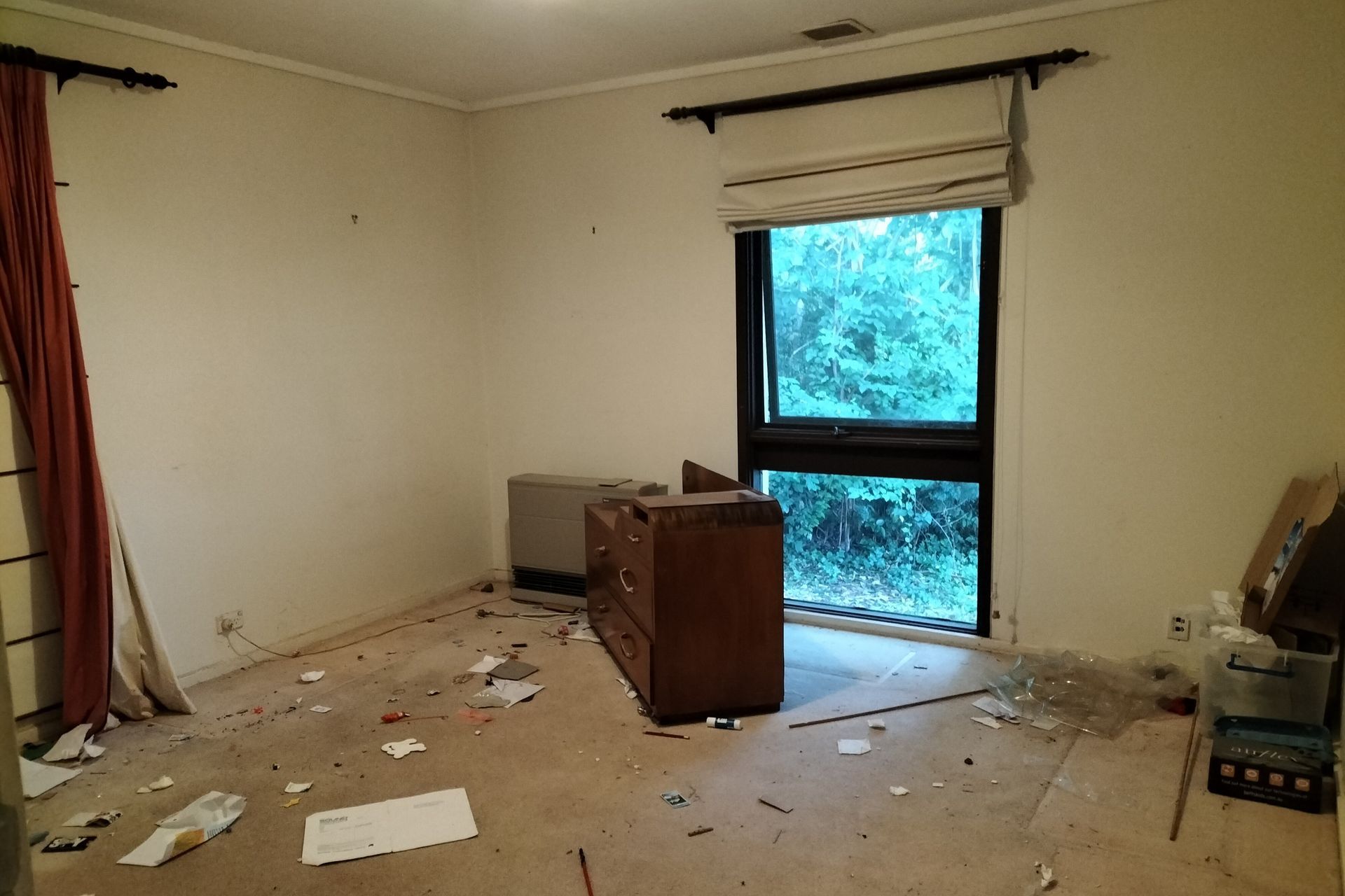 Cluttered dining room with table covered in clothes and items; two framed art pieces on the wall.