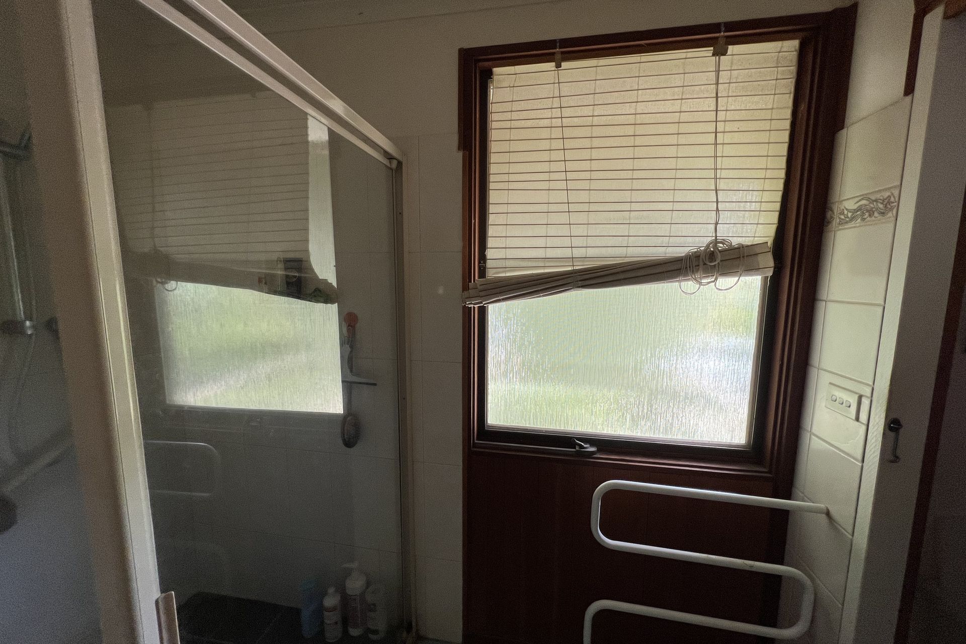 Cluttered dining room with table covered in clothes and items; two framed art pieces on the wall.