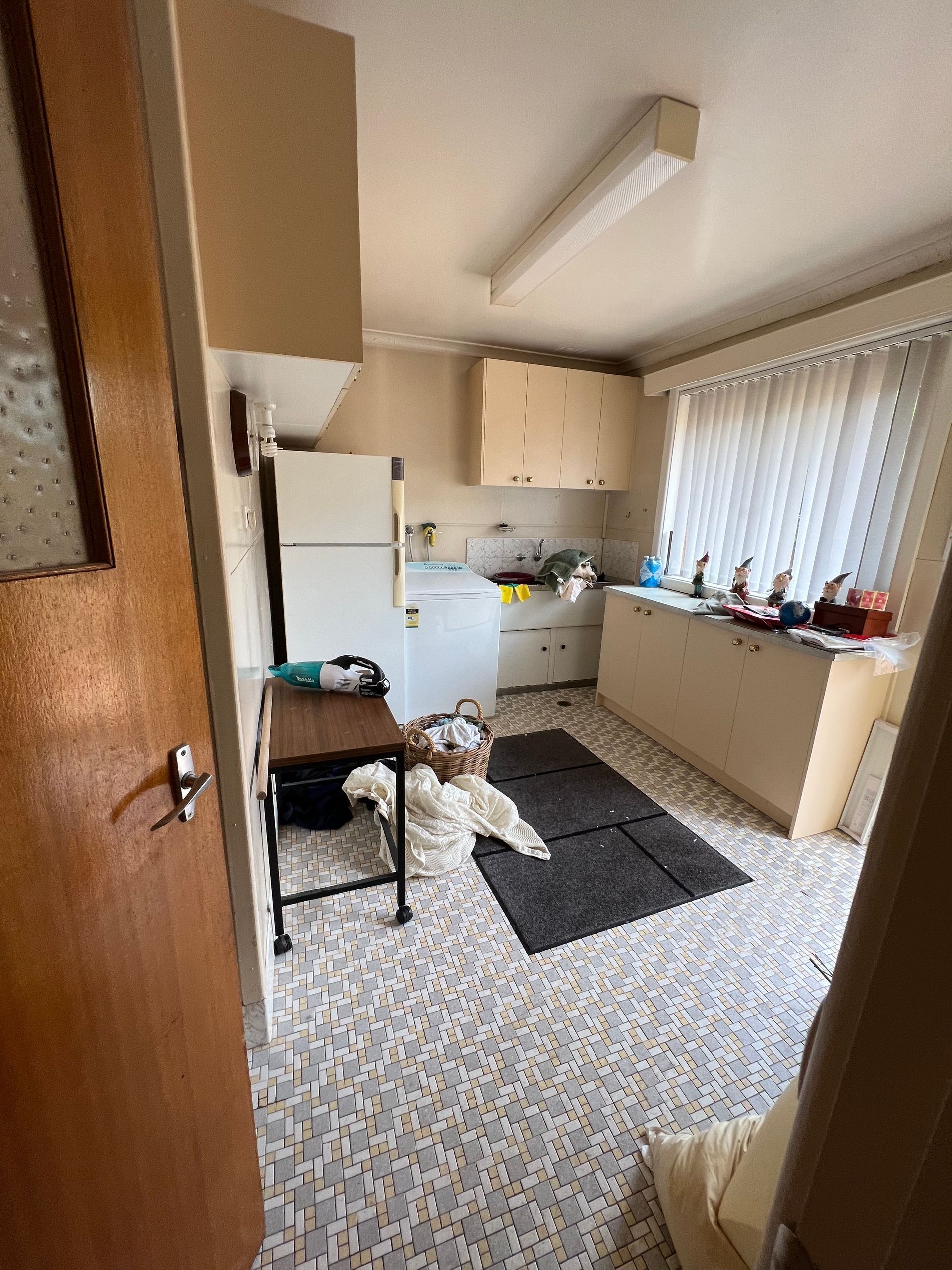 Dilapidated utility room with a sink, counter, and peeling wallpaper.