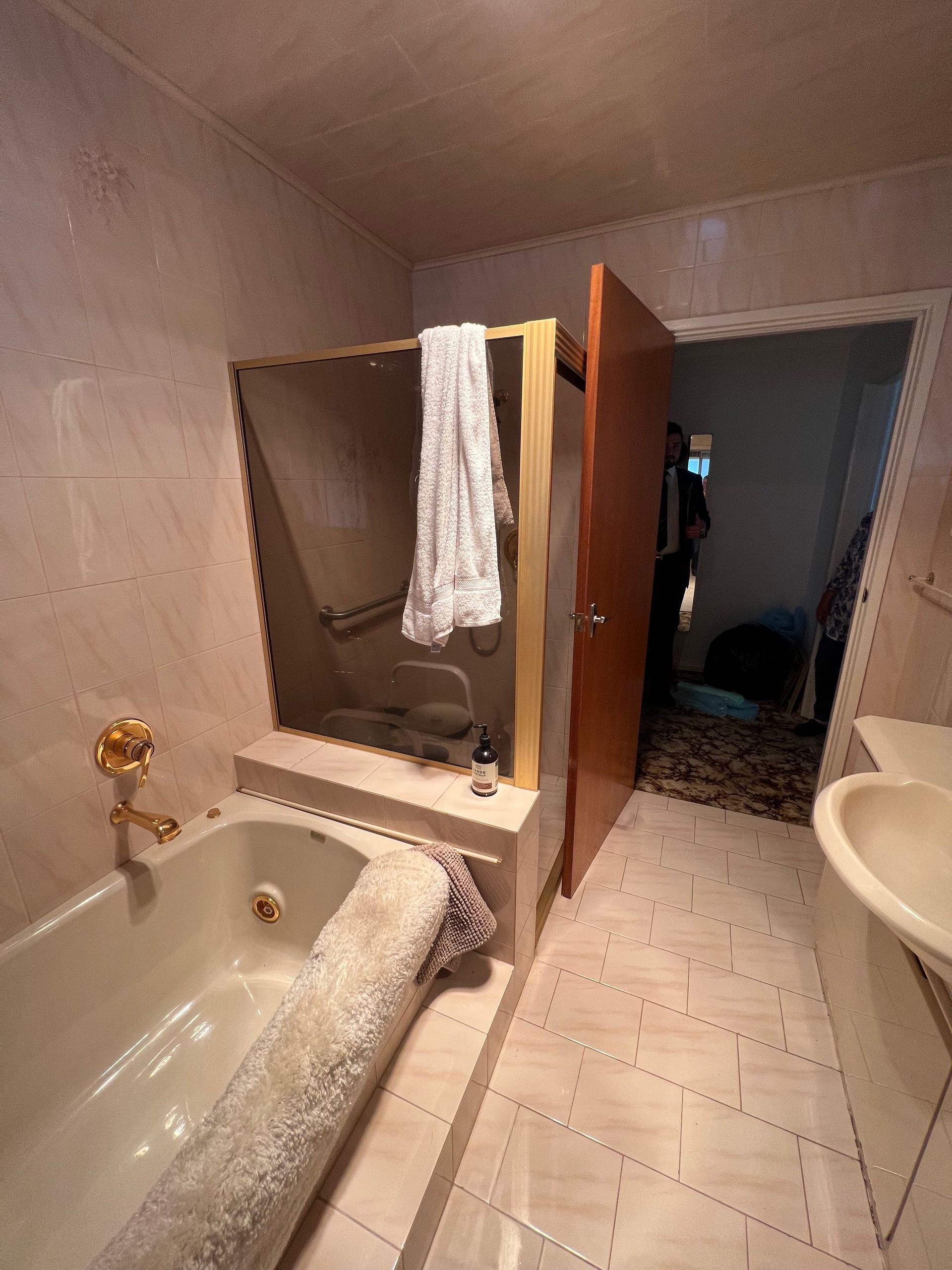 Bathroom with a bathtub, shower, and open door to another room.