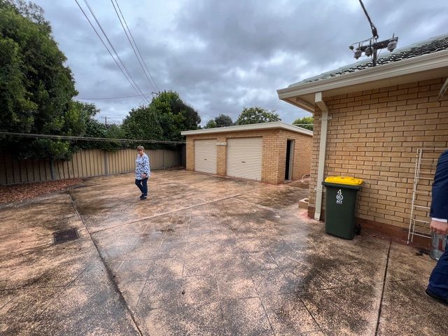 Backyard with a detached garage, cloudy sky, person walking.