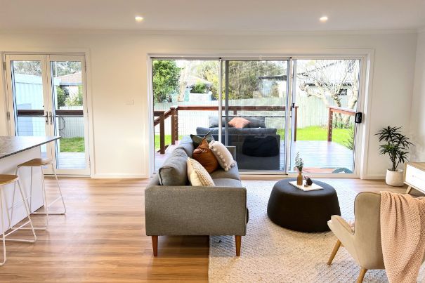 Living room with sliding door to deck, gray sofa, chair, and coffee table.