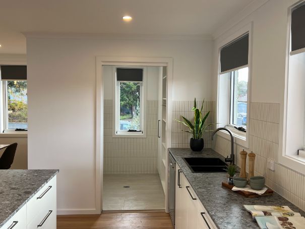 Kitchen with granite countertops, black sink, and a view through a doorway to a bathroom with a window.