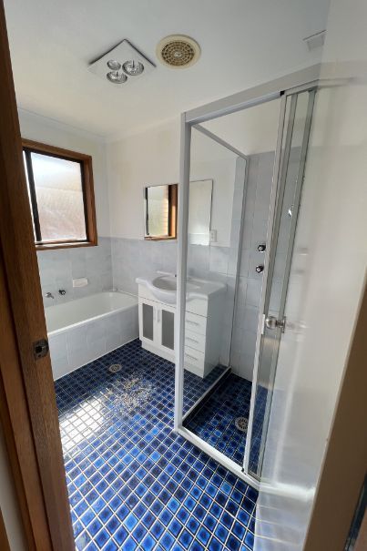 Bathroom with blue patterned floor, white fixtures, and a glass shower.
