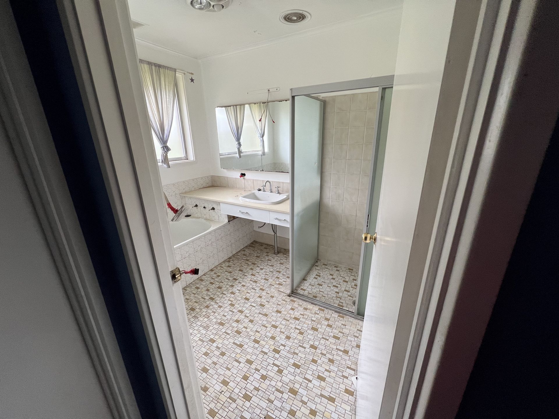 Interior view of a room with blue walls, a brown floor, and large windows looking outside.