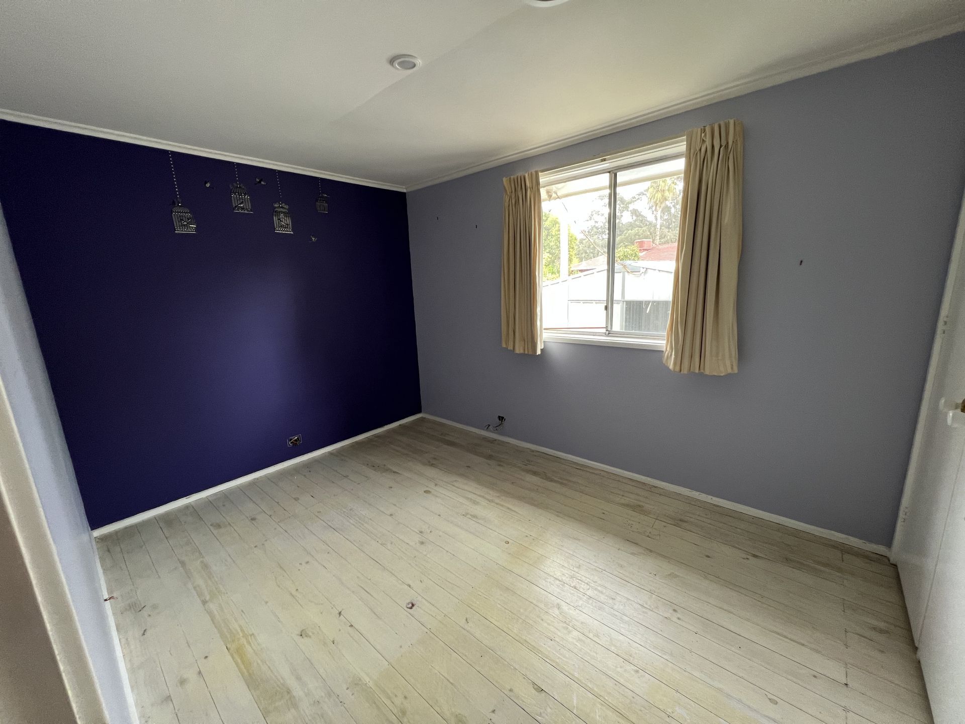 Empty room with blue walls, sliding glass door, and worn flooring.