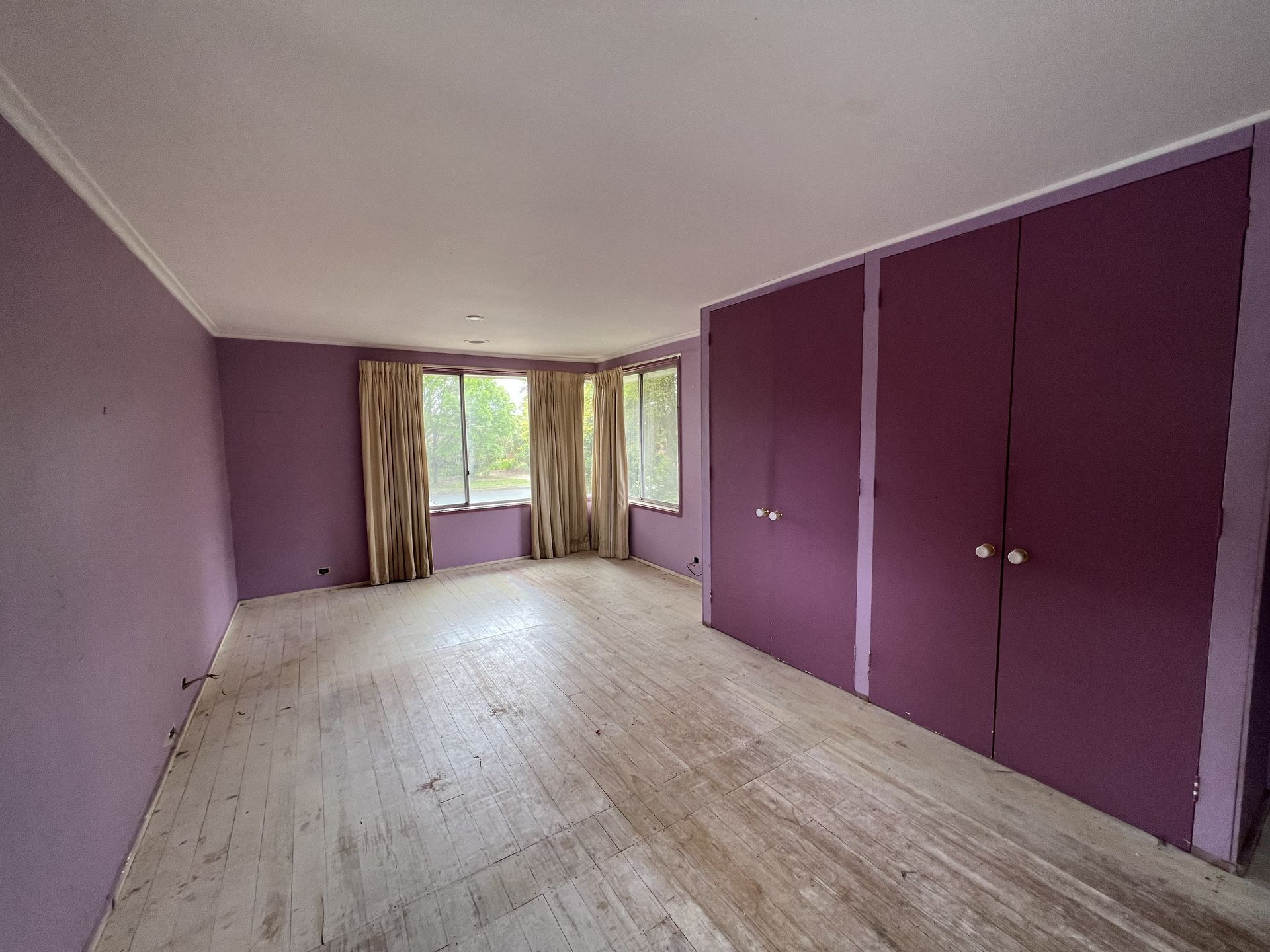 Empty room with blue walls, sliding glass door, and worn flooring.