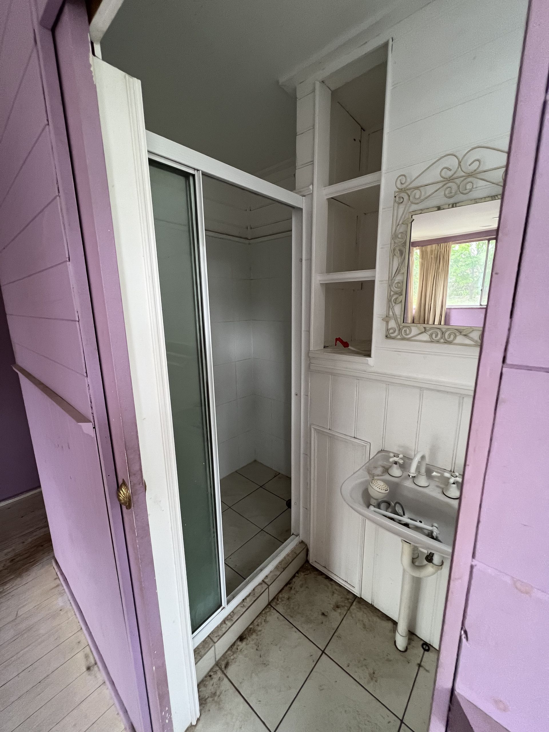 Small bathroom with a sliding glass shower door and sink. Walls are pink and white.