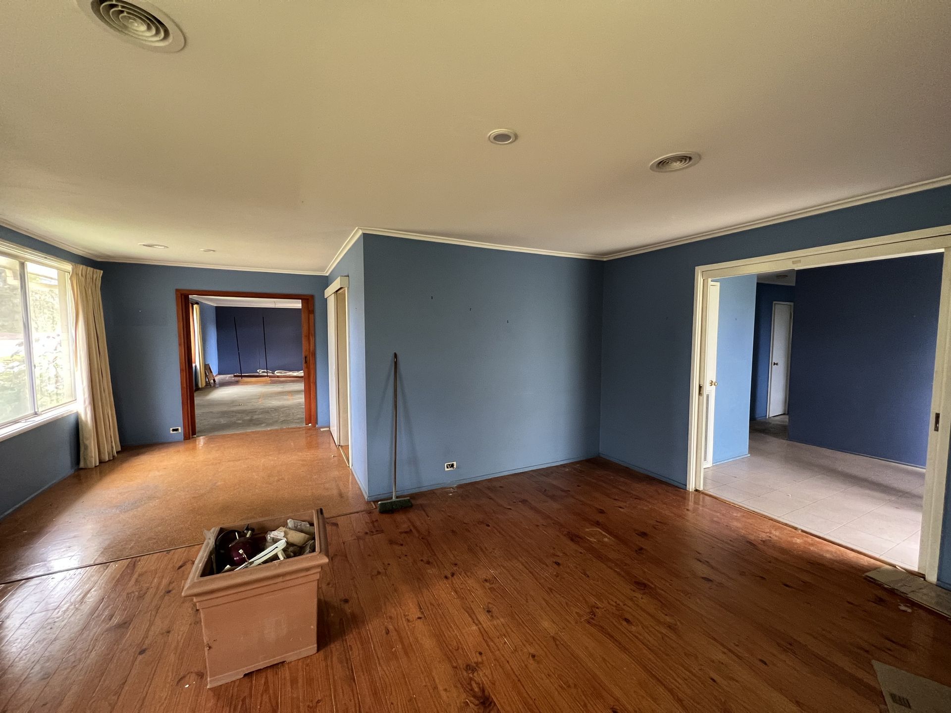 Empty room with blue walls, sliding glass door, and worn flooring.