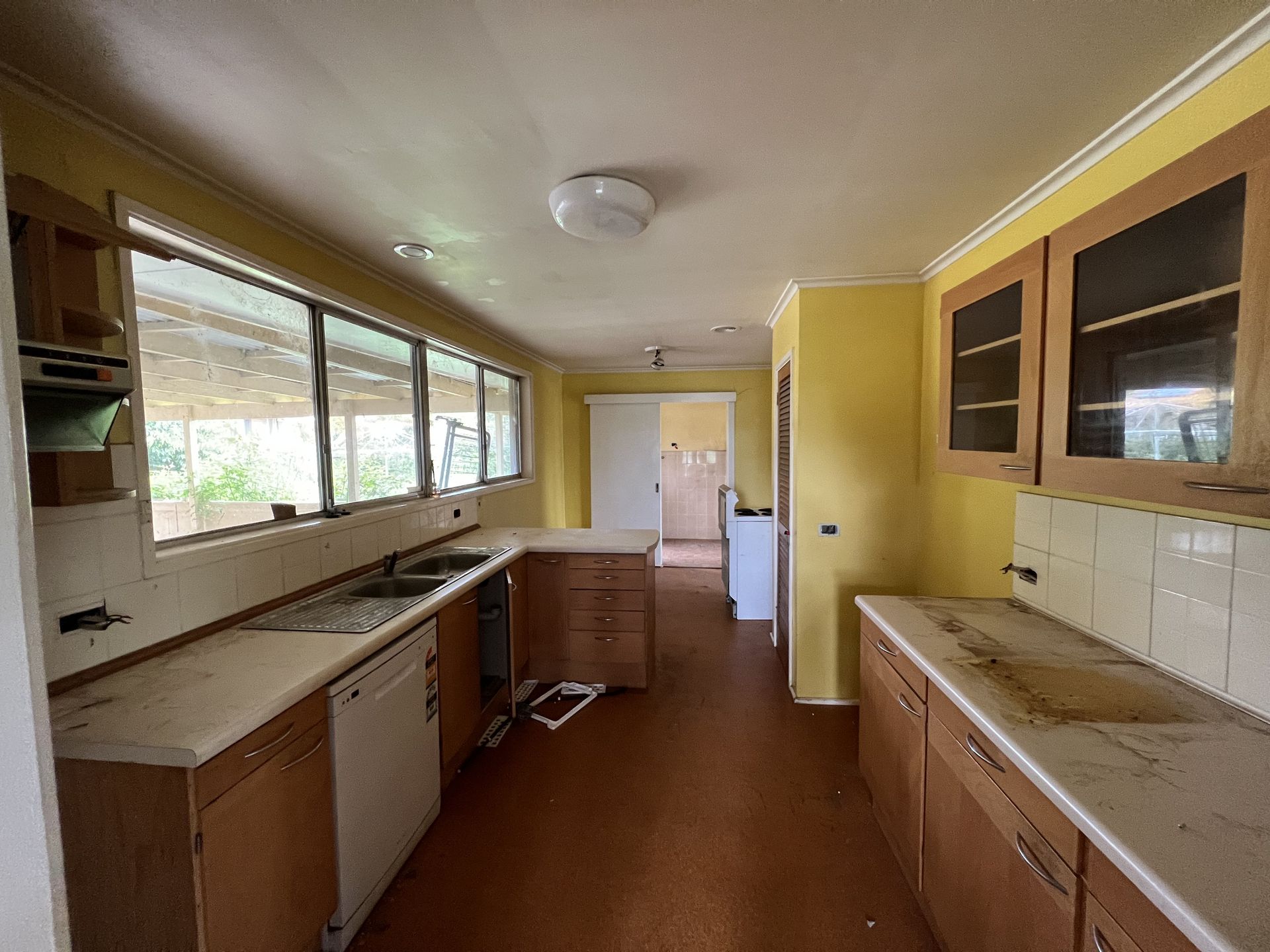 Dilapidated utility room with a sink, counter, and peeling wallpaper.
