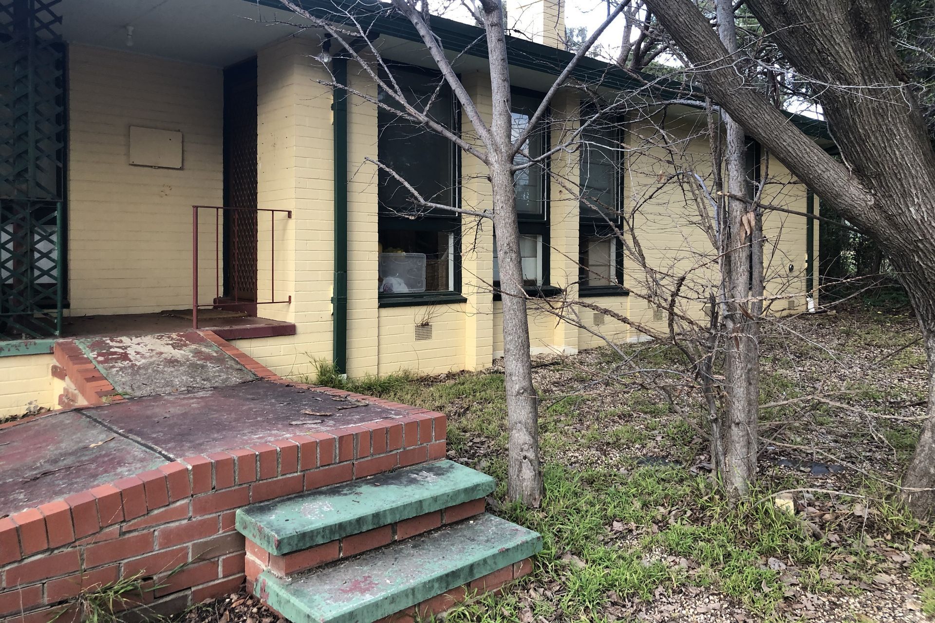Cluttered dining room with table covered in clothes and items; two framed art pieces on the wall.