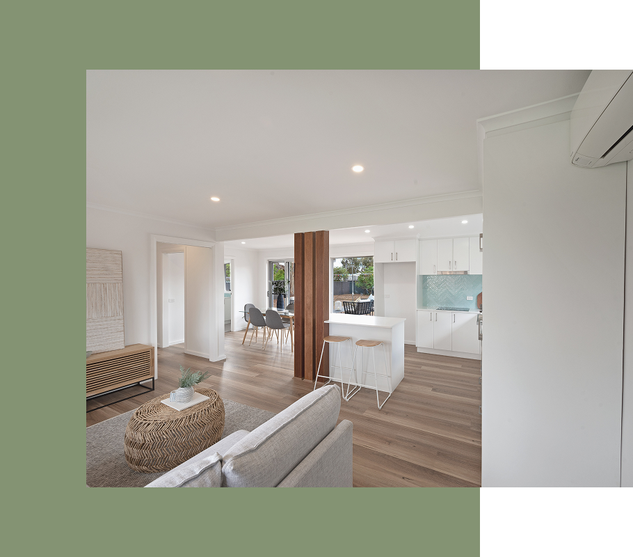 Bright, open-plan living space with light wood flooring, white walls, and a ceiling fan.