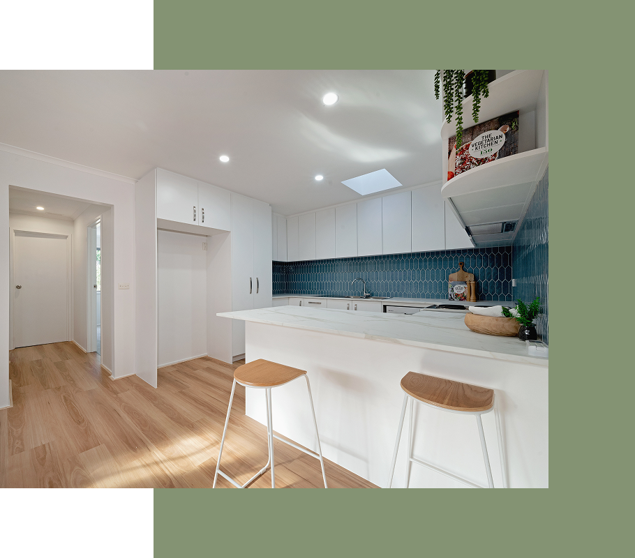 Modern white kitchen with blue tile backsplash, wooden floors, and bar stools.