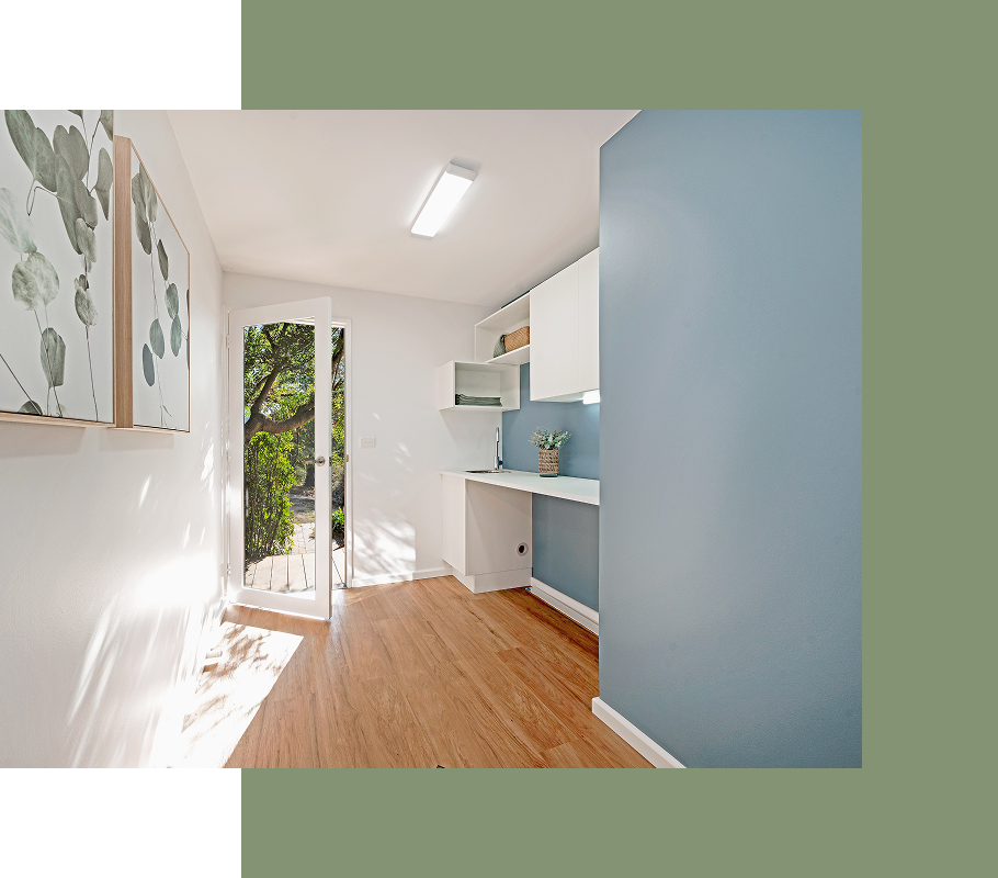Bright office with wood floor, white walls, blue accent wall, desk, open door to greenery.