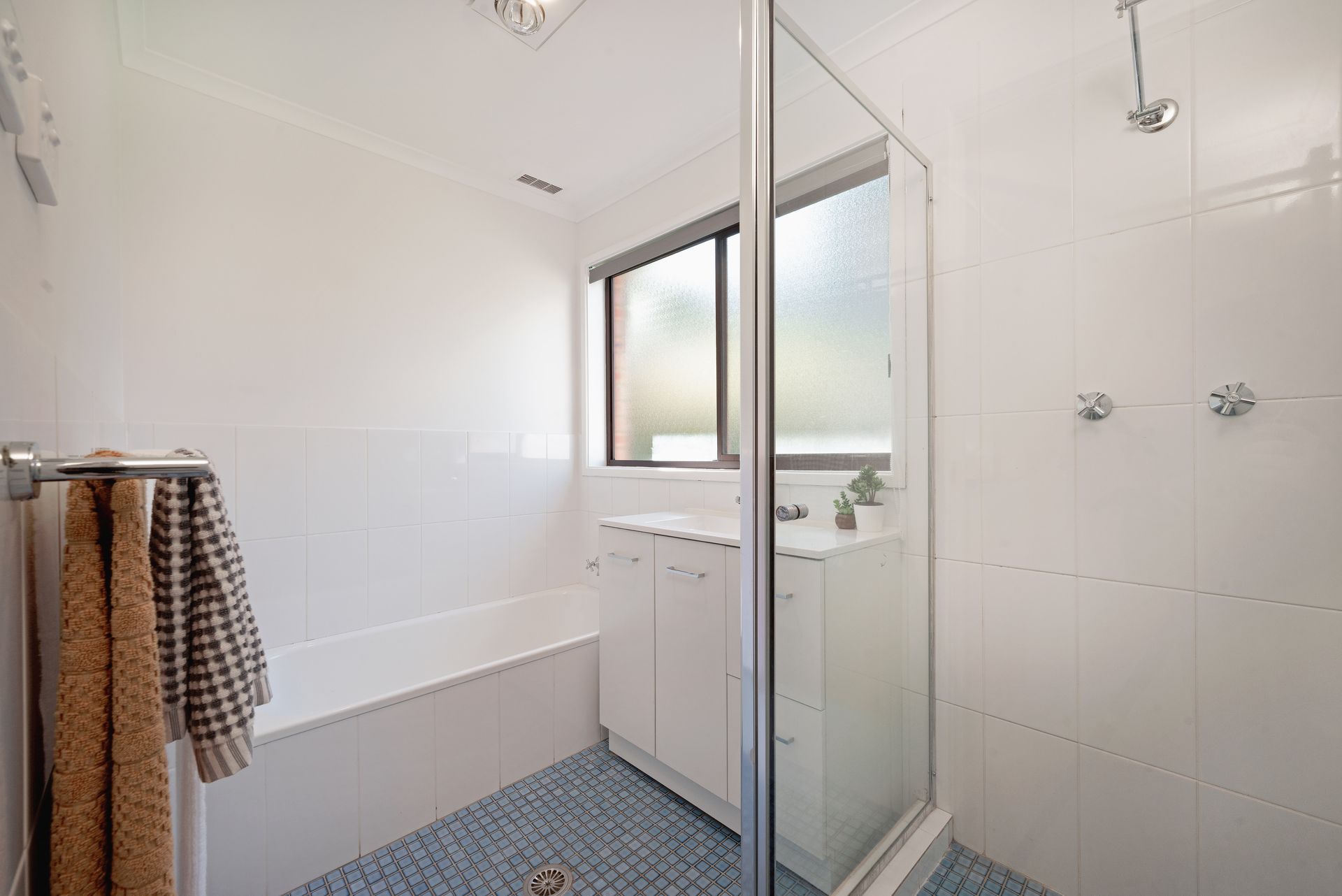 White laundry room with sink, counter, cabinets, and door to outside. Plant and laundry basket are present.