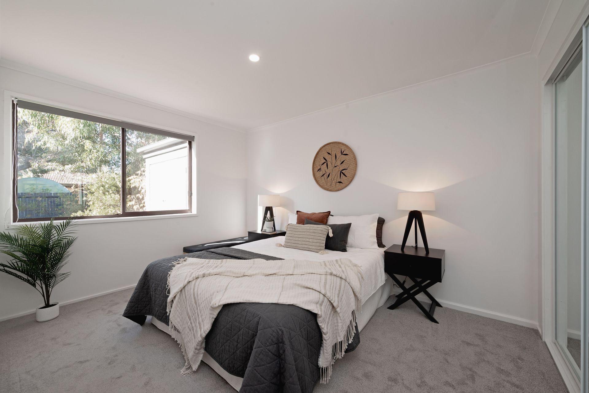 Bedroom with bed, nightstands, window, and decorative wall art.