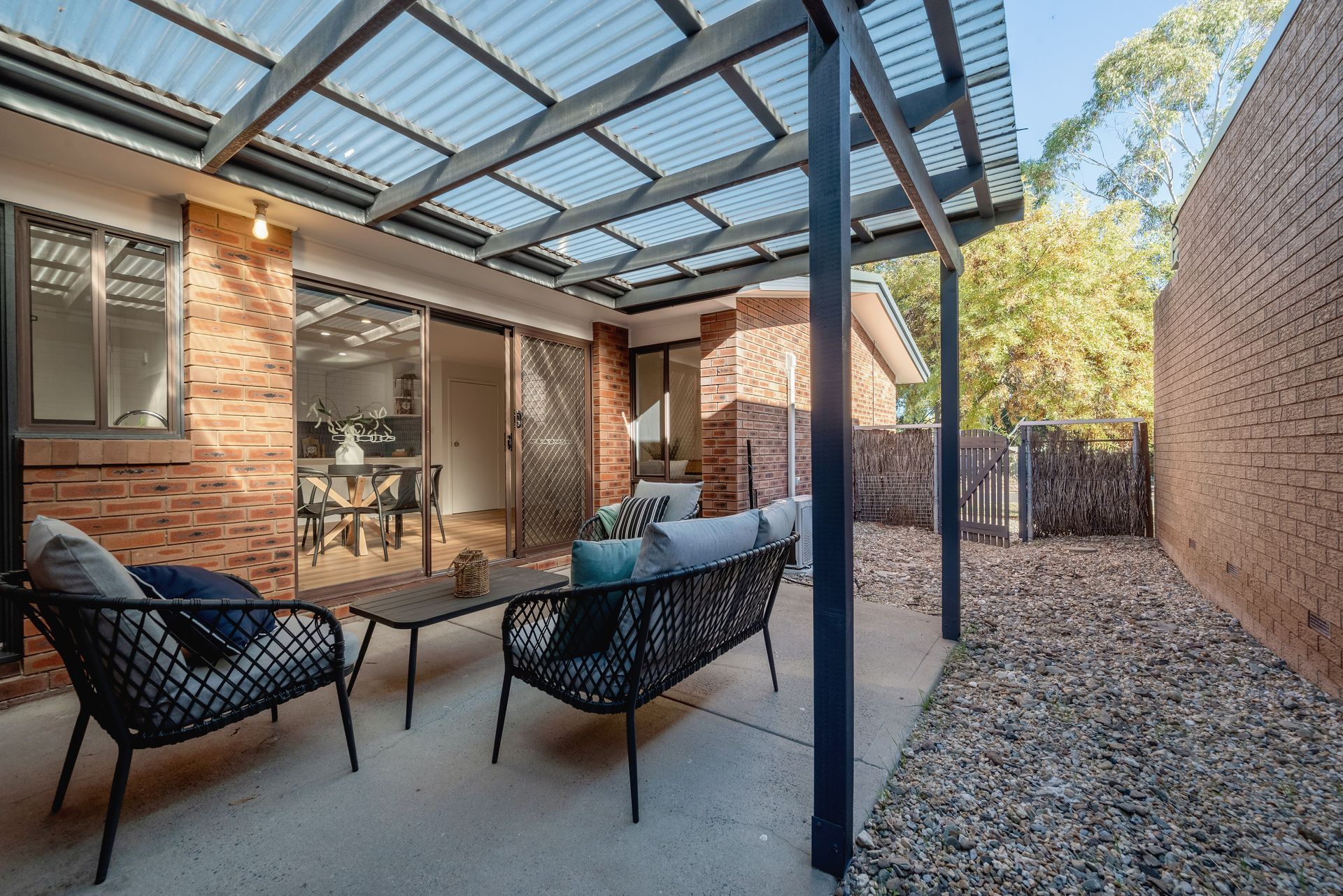 Patio with seating under a corrugated roof; brick walls on either side.