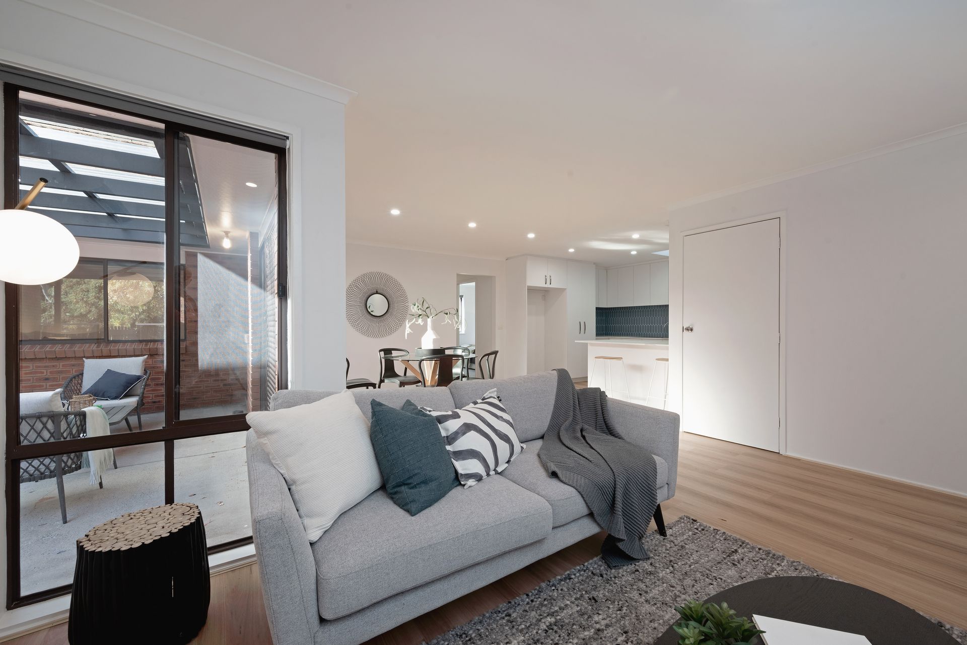 Living room with gray sofa, large window to patio, neutral tones.