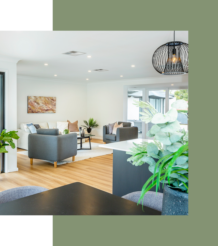 Open-concept living room with gray and white furniture, hardwood floors, and a decorative light fixture.