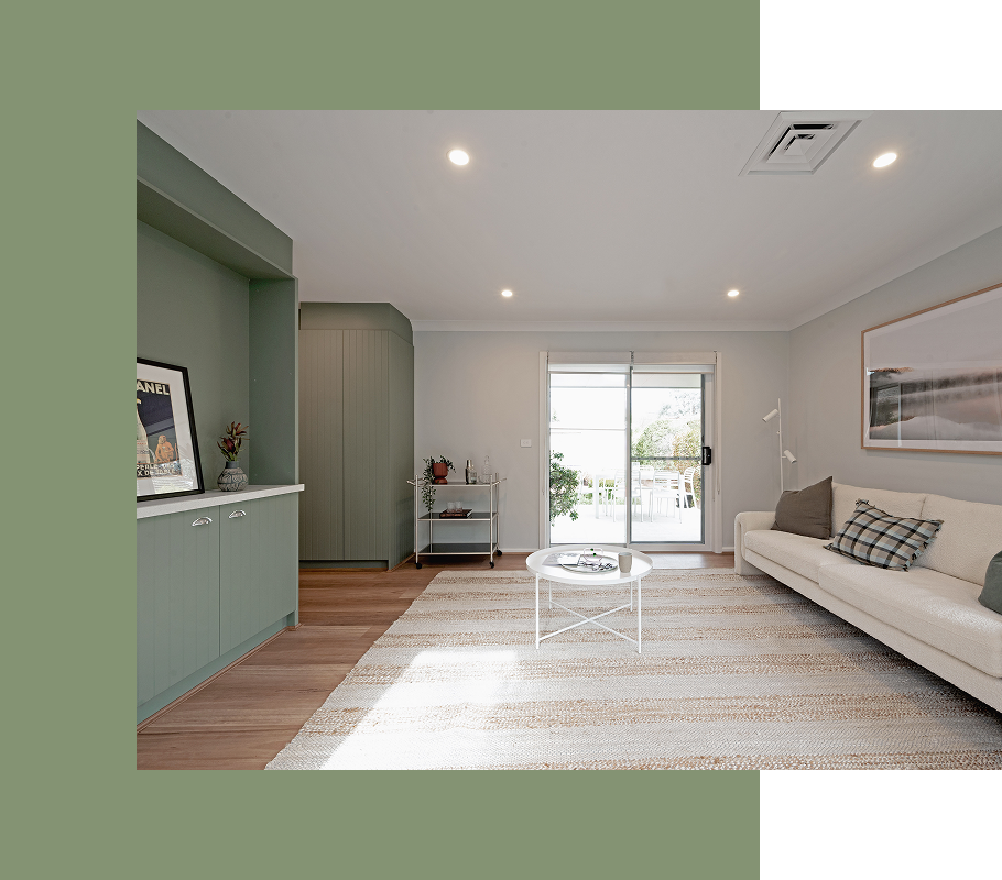 Living room with green built-in cabinetry, white sofa, and sliding glass door.