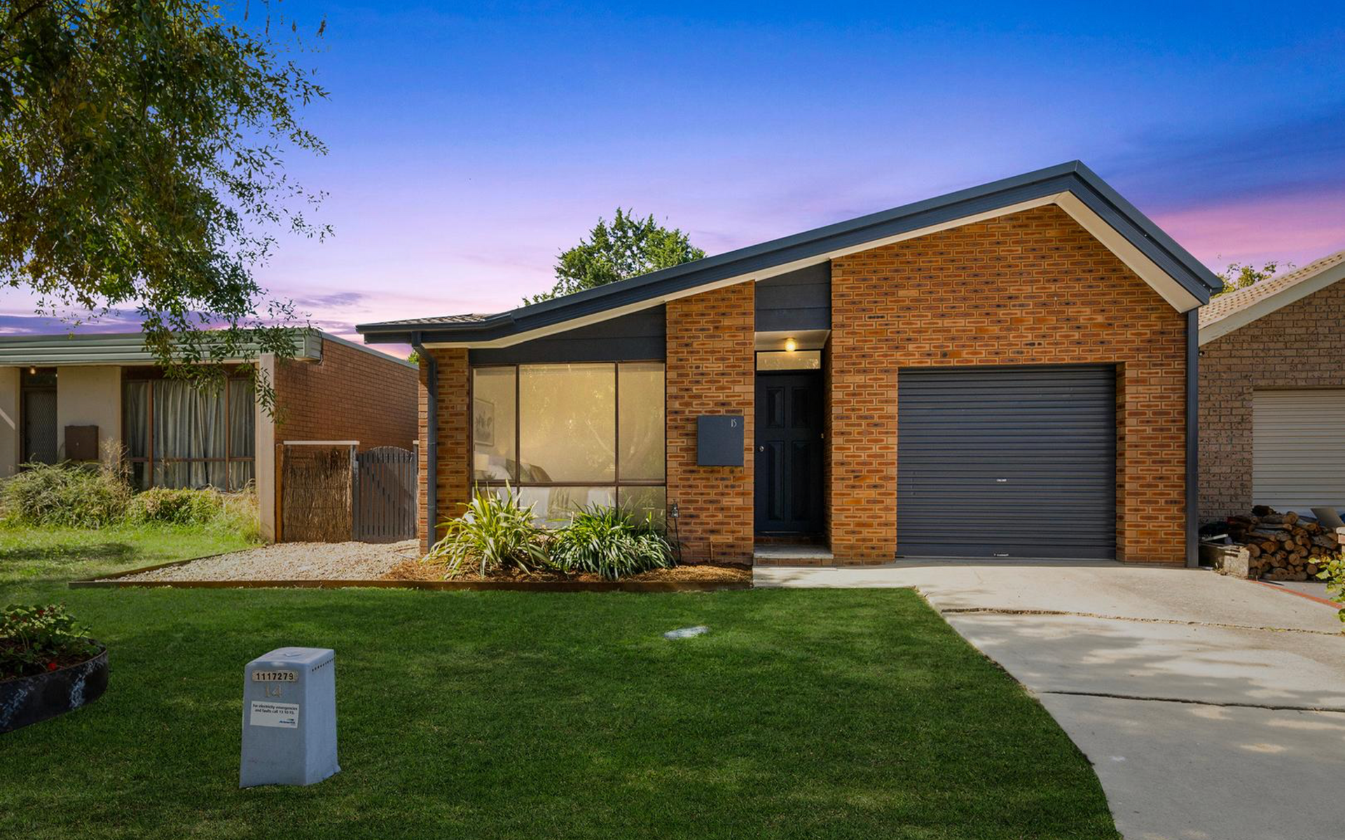Brick house with a slanted roof, garage, and front yard with grass and driveway.