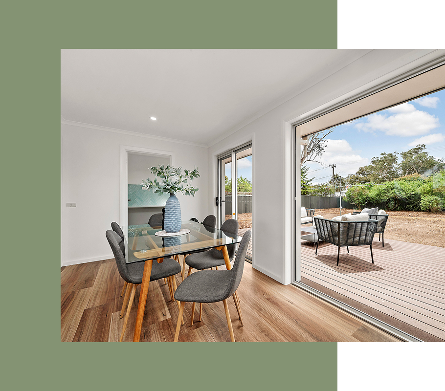 Dining room with glass table, gray chairs, and open sliding doors to a patio.