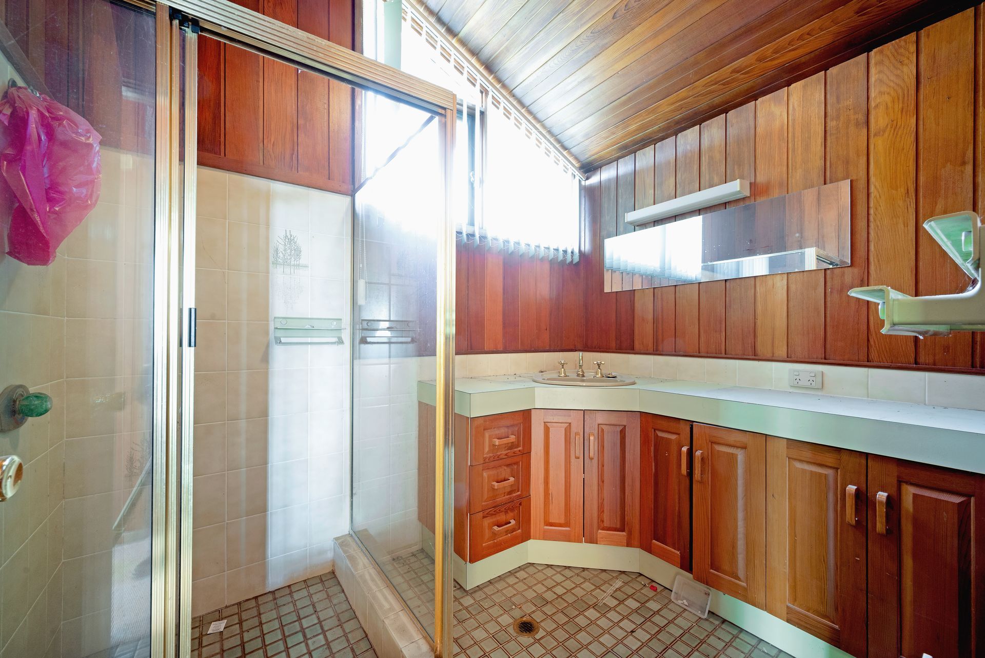 Empty room with wood paneling on walls and ceiling, two windows, and a metal step stool.
