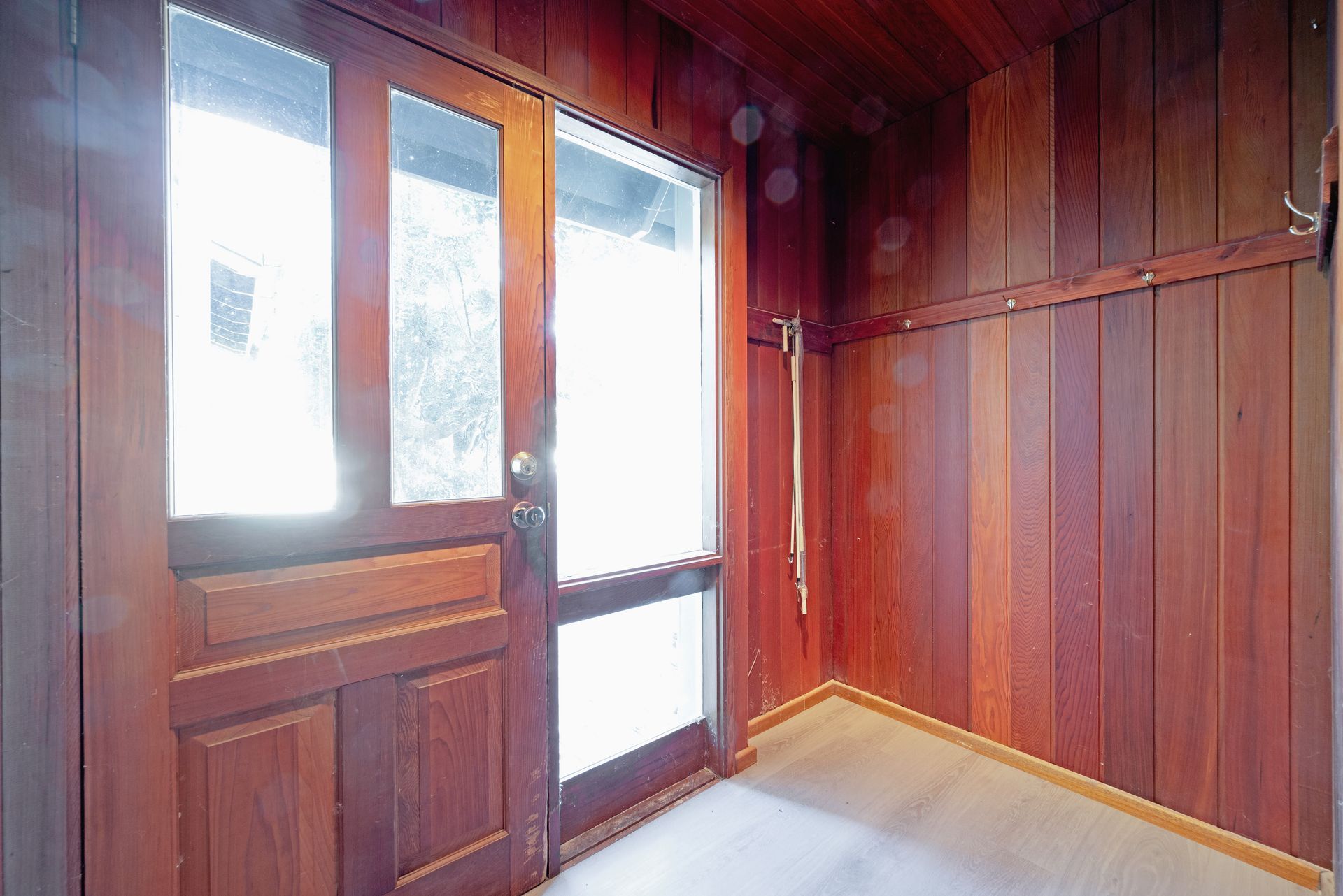 Wooden entryway with door and window; bright light shines through.