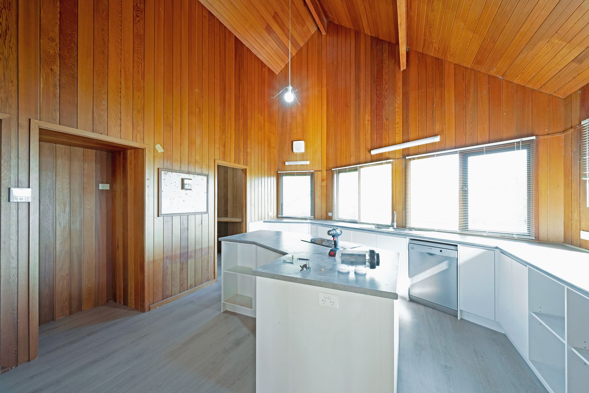 A messy kitchen with grey cabinets, a window, and appliances on the counter.