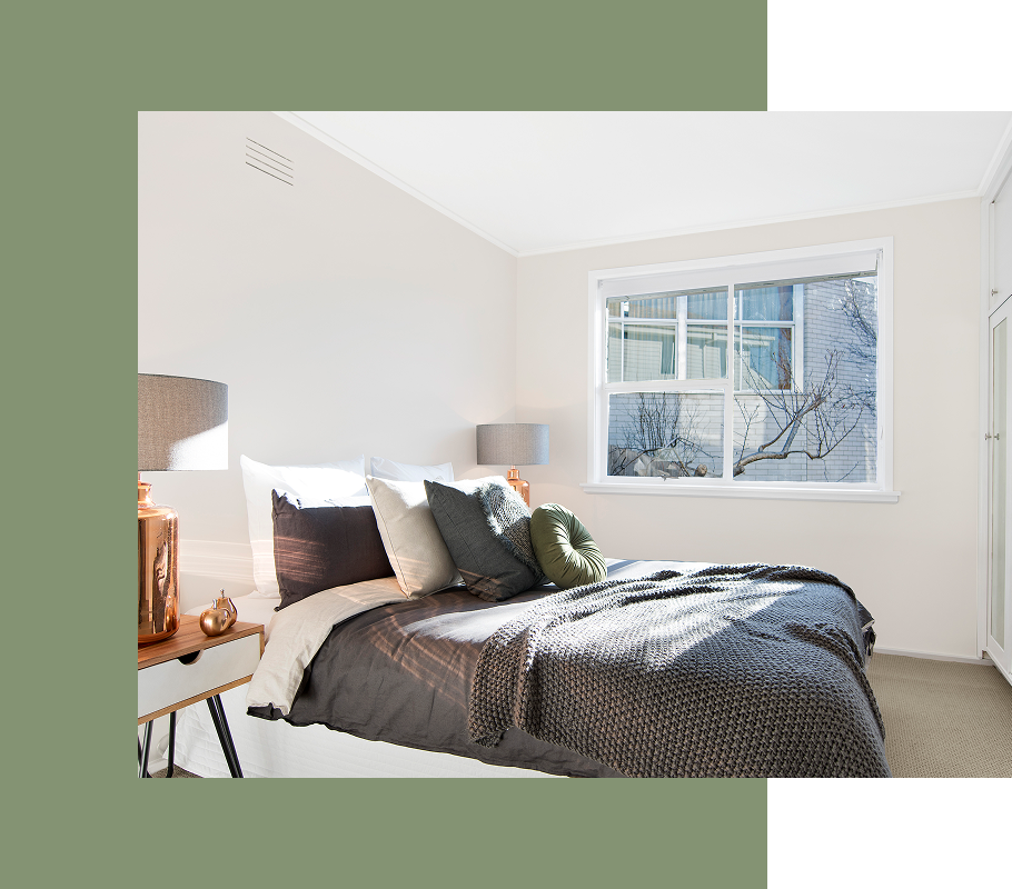 Bedroom with a bed, nightstand, window, and neutral-toned decor. Sunlight streams in.