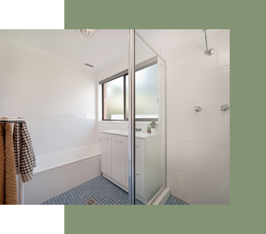 Bathroom with shower, tub, and vanity; blue tile floor, white walls, glass shower door, and a towel rack.