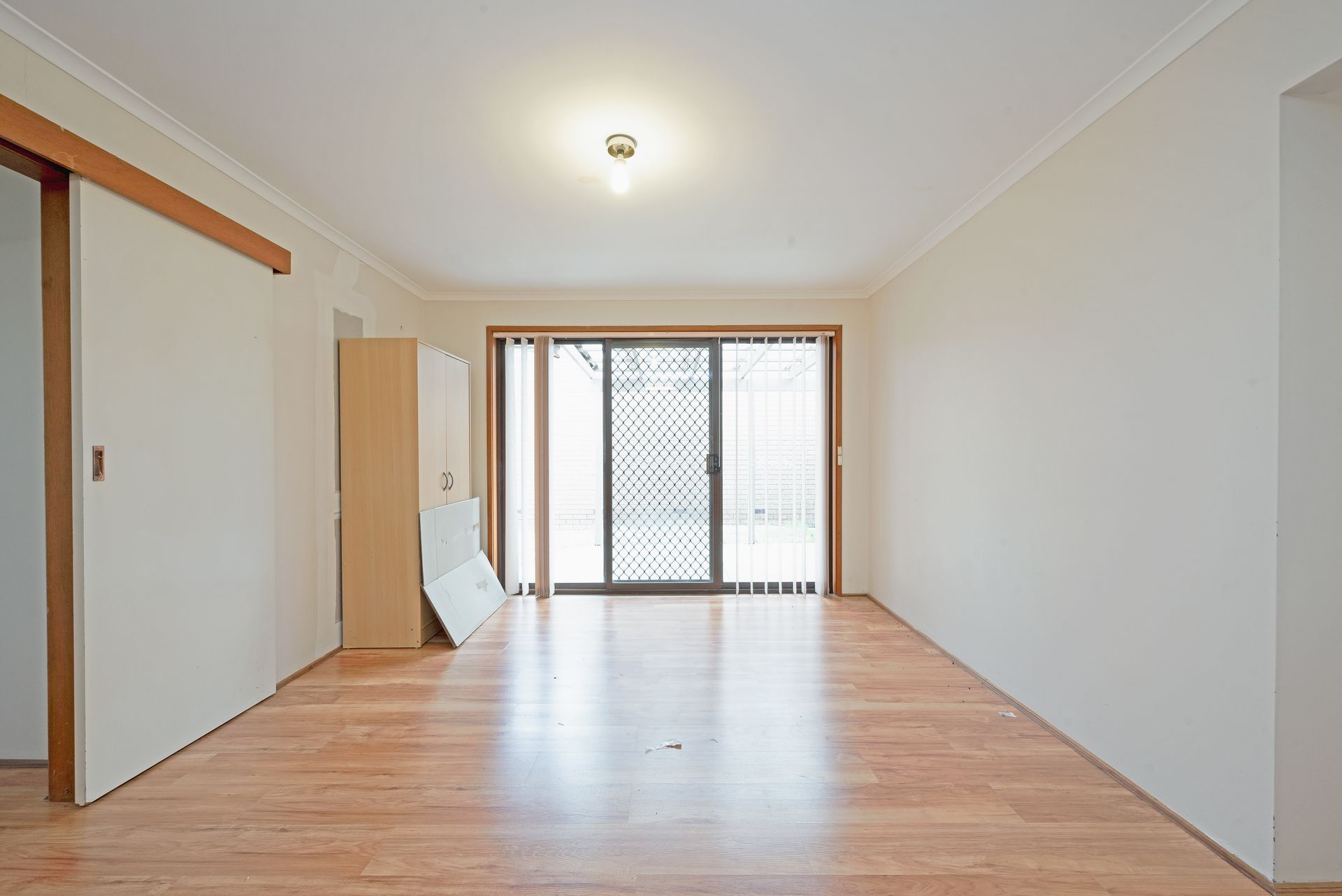 Empty room with wood floors, sliding glass door, and white walls.