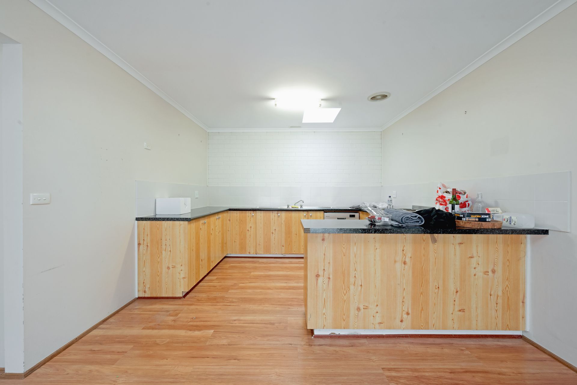 Kitchen with light wood cabinets, dark countertop, and wood floor.