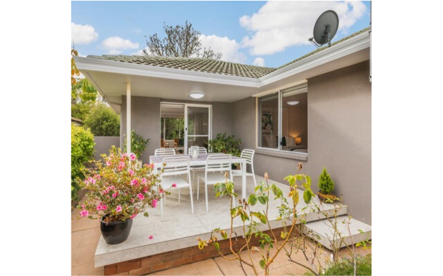 Outdoor patio with white furniture, potted flowers, and a satellite dish.