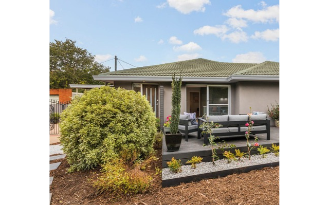 Exterior view of a house with patio furniture and a landscaped garden.
