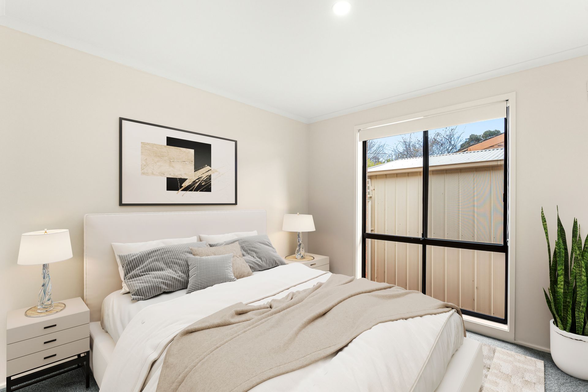 Bedroom with bed, nightstands, window, artwork, and a potted plant.