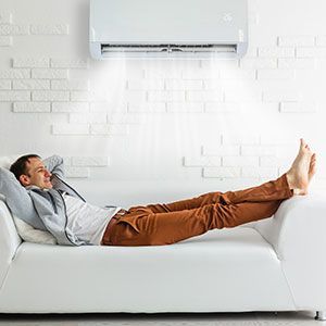 Man relaxing on couch under air conditioner.
