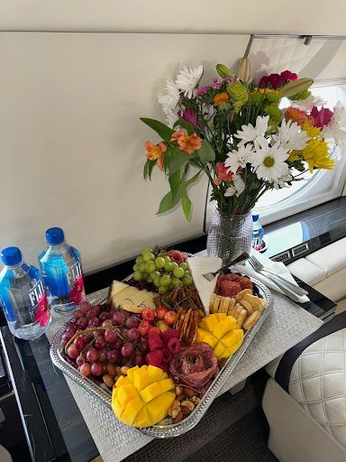 There is a tray of fruit and flowers on the table.
