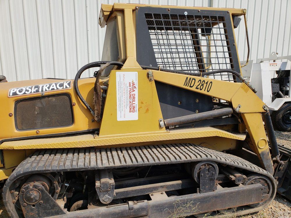 A yellow post track bulldozer is parked in front of a building