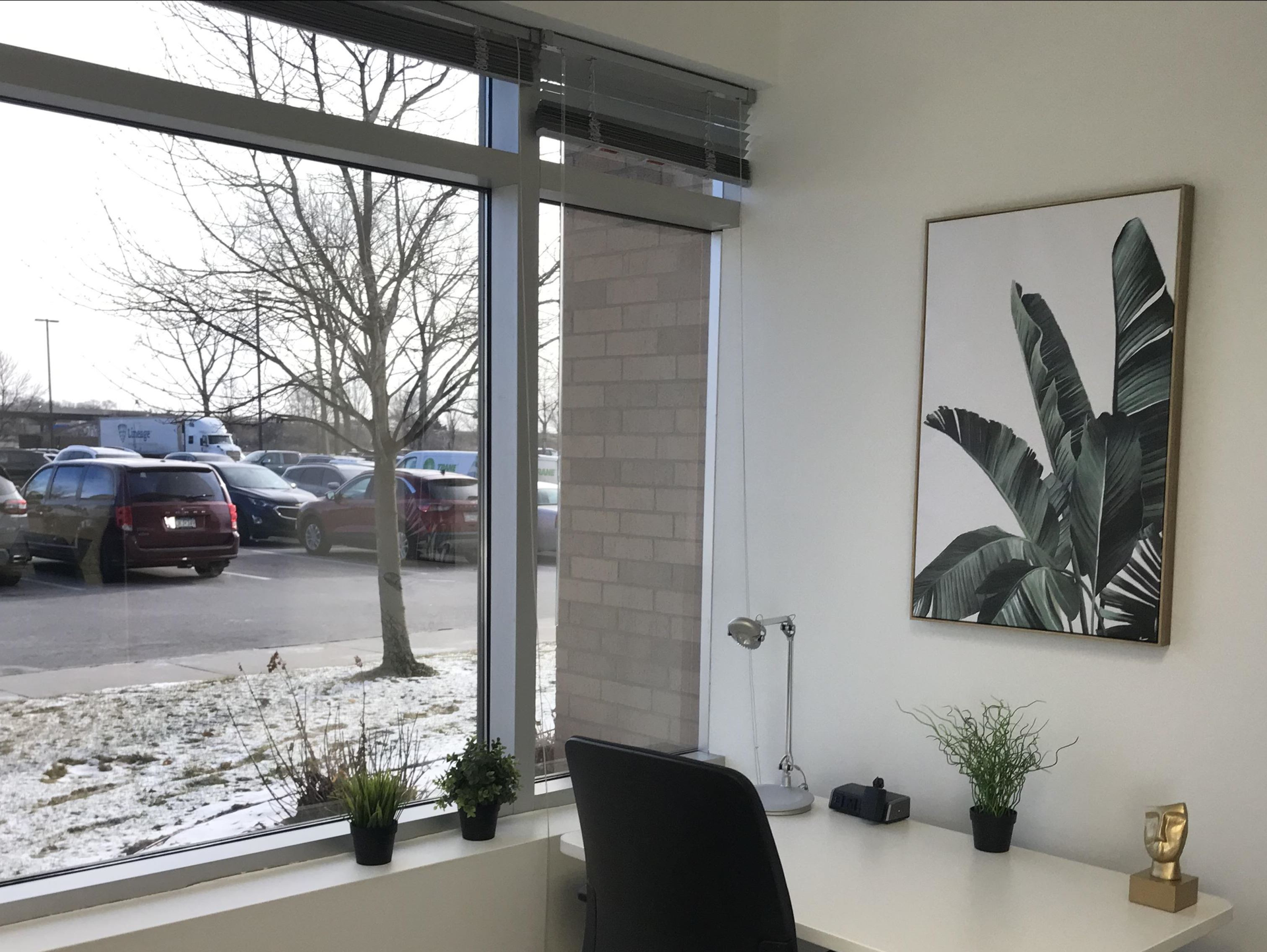 A room with a desk and chair and a picture on the wall.