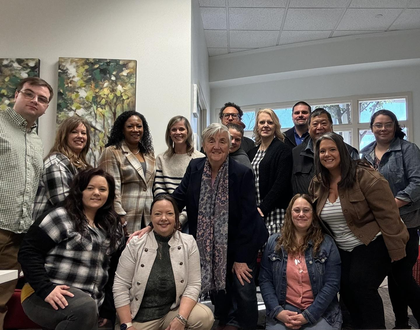 A group of people are sitting at desks in an office.