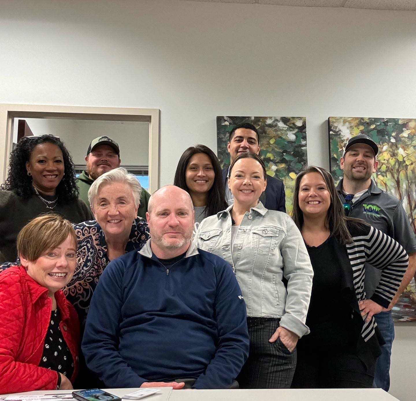 A group of people are sitting at desks in an office.