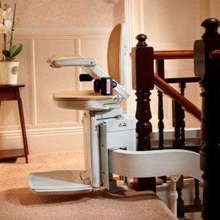A stair lift sits next to a wooden staircase