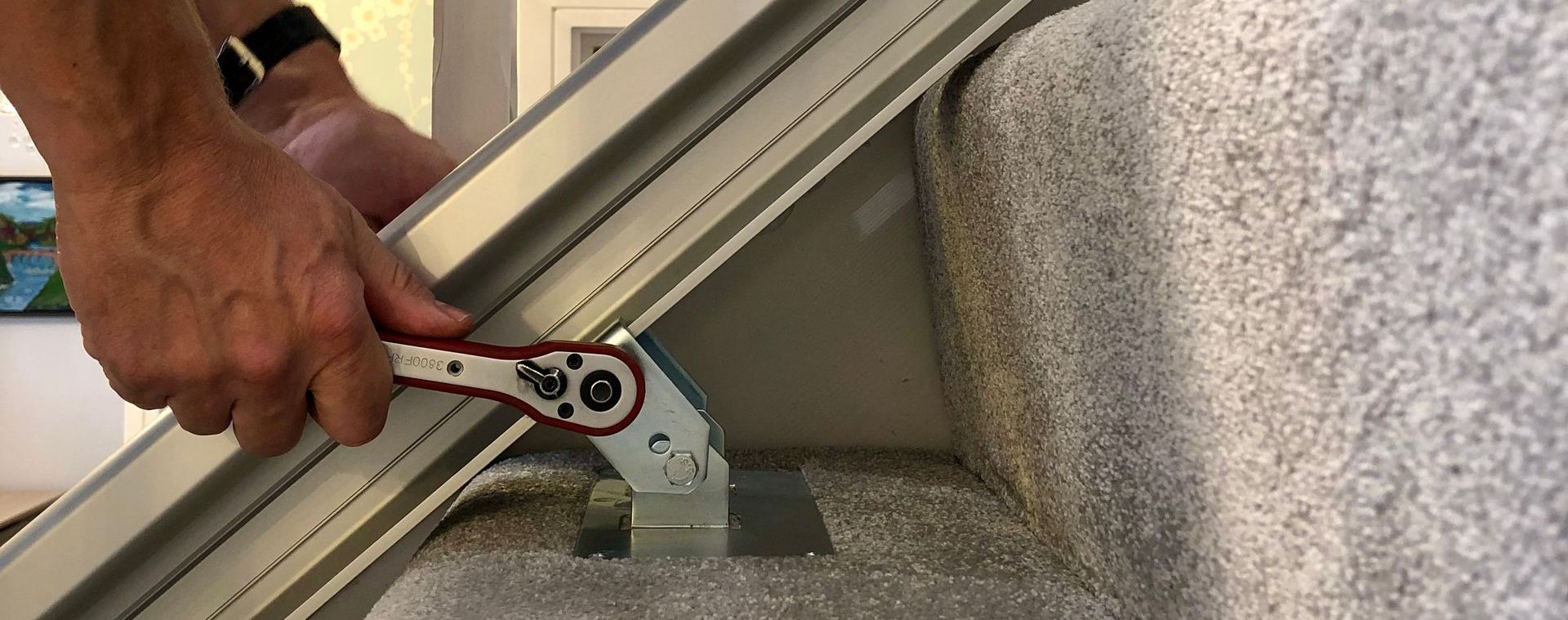 A person is holding a wrench next to a staircase.