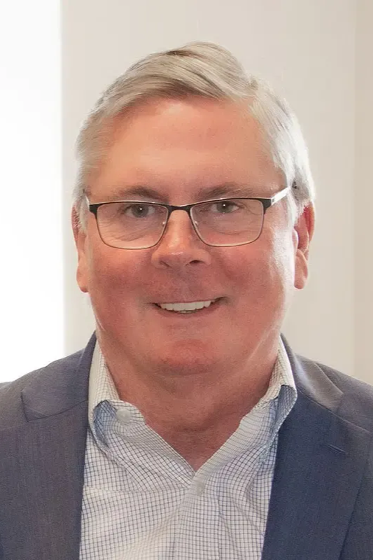 A woman wearing glasses and a black and white polka dot shirt is smiling for the camera.
