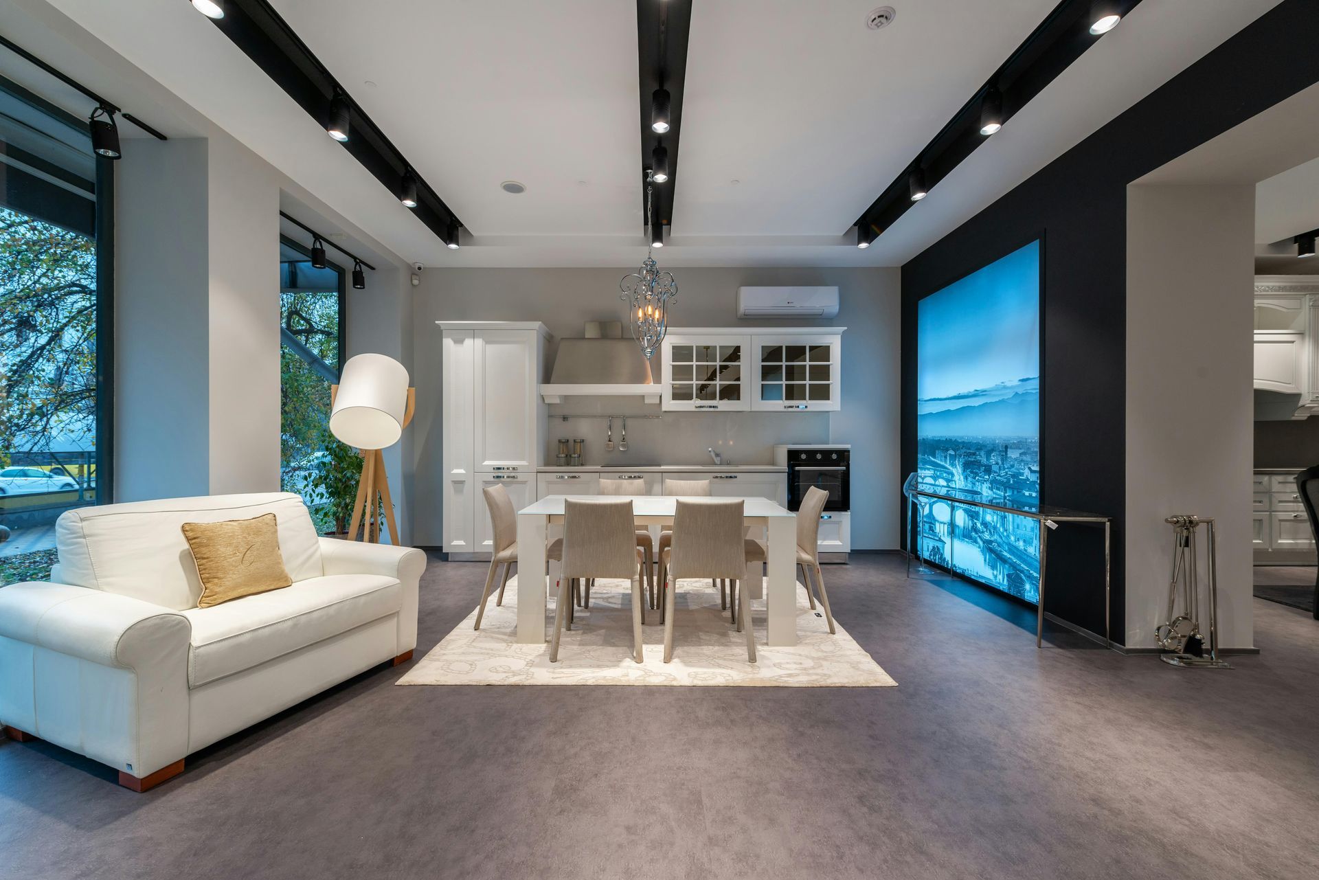 Modern kitchen and dining room display with white sofa, table, and cabinetry, featuring large scenic artwork.