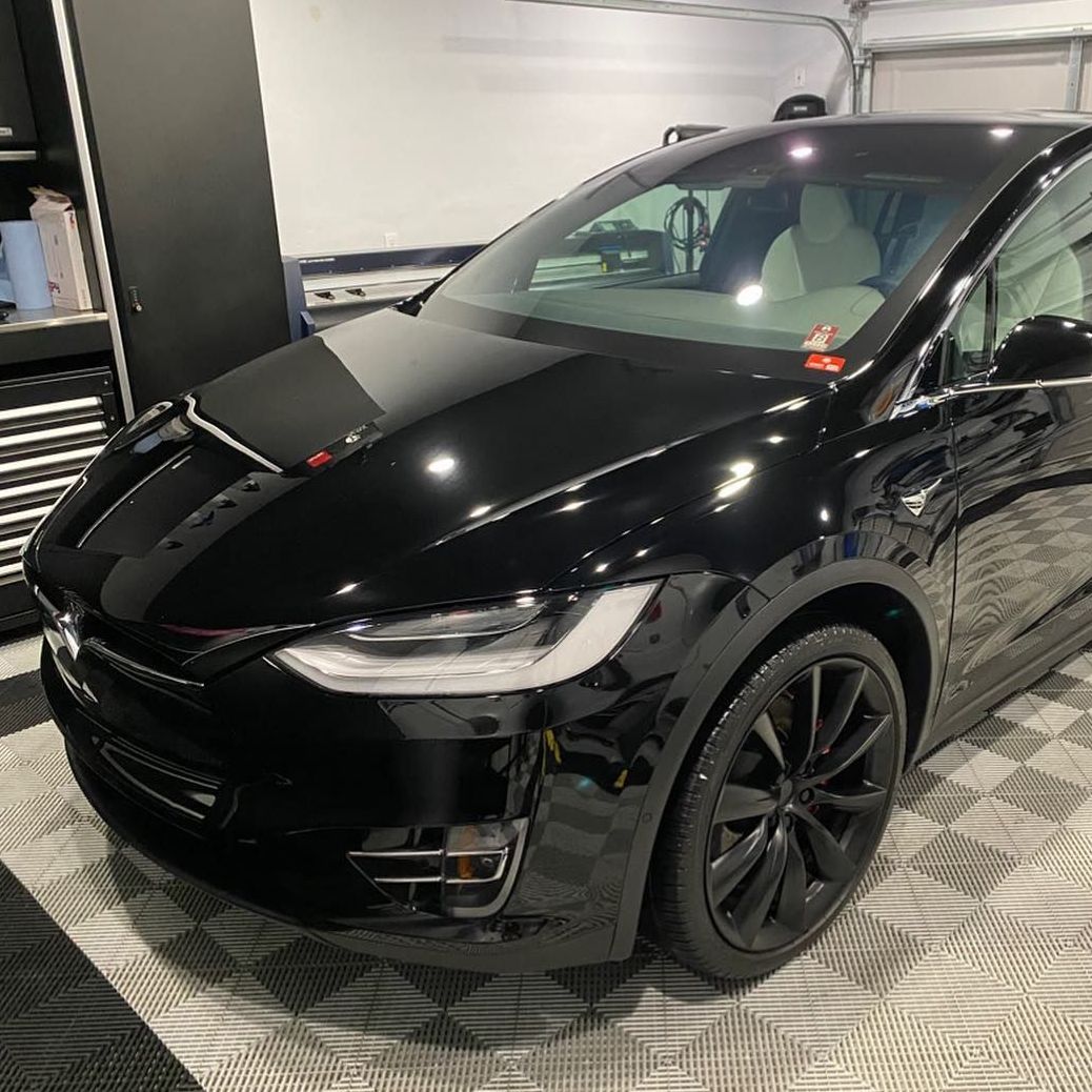 A black tesla model x is parked in a garage.