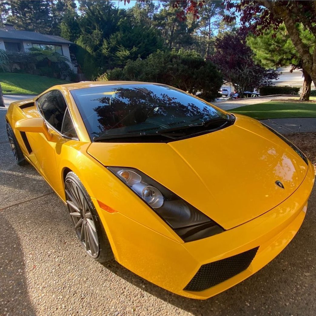 A yellow lamborghini is parked in a driveway in front of a house