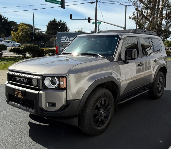 Silver Toyota Land Cruiser parked at an intersection on a sunny day