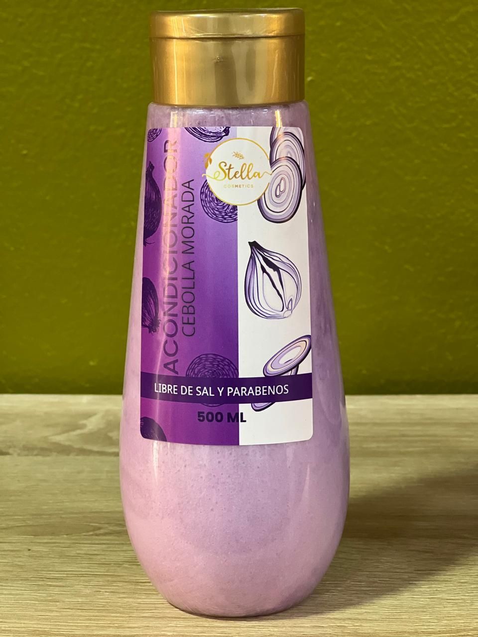Botella de acondicionador morado, con gráficos de cebolla morada, sobre una superficie de madera sobre un fondo verde.